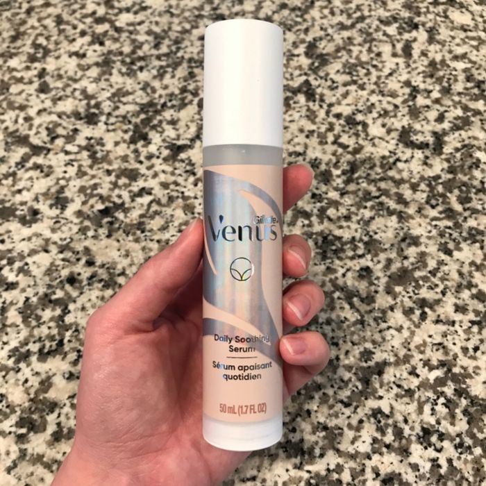 A hand holding a bottle of Venus Daily Soothing Serum against a speckled countertop surface