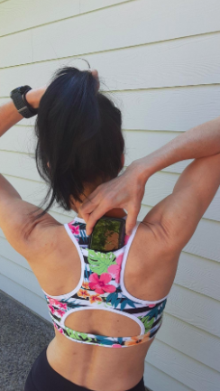 A reviewer sliding a smartphone into the back pocket of a floral racerback sports bra.
