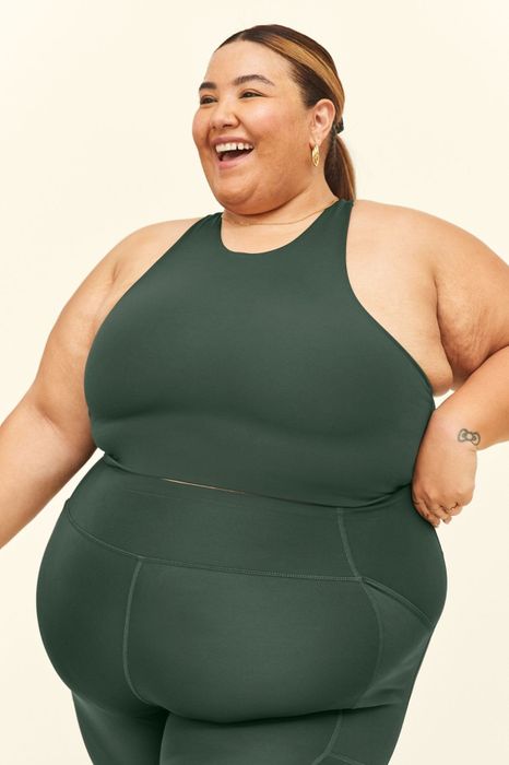 The model is wearing a green sports bra paired with matching leggings.