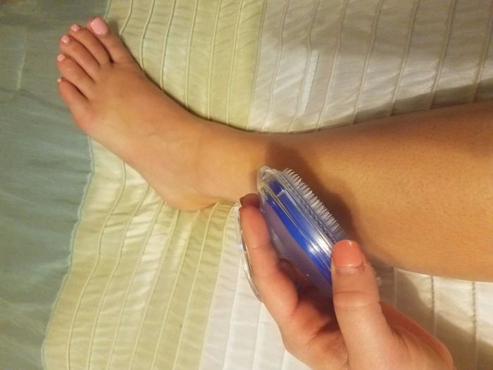 Reviewer's photo of the exfoliating brush in blue being used on their leg
