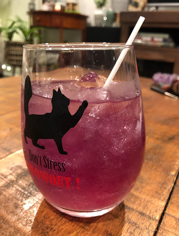 Pink edible glitter shimmering in a wine glass with a fancy cocktail