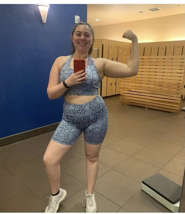 A reviewer showcasing a blue snake print sports bra and bike short set.