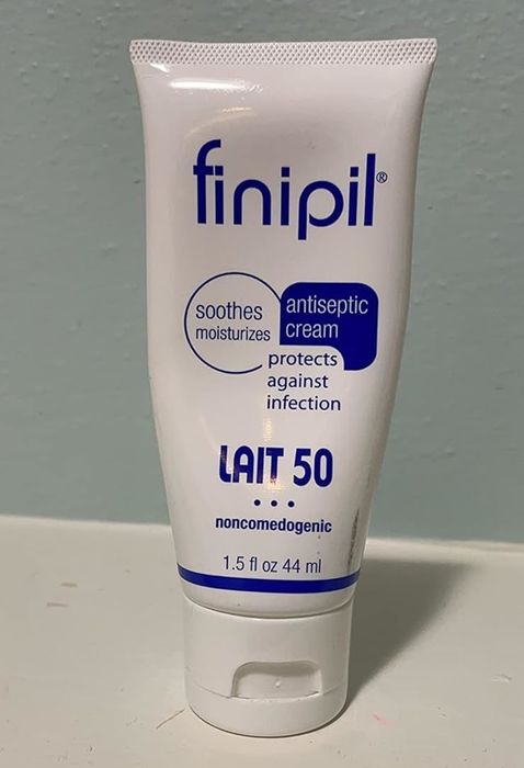 A reviewer’s photo showing a tube of Finipil Lait 50 lotion, used for soothing and protecting the skin post hair removal.