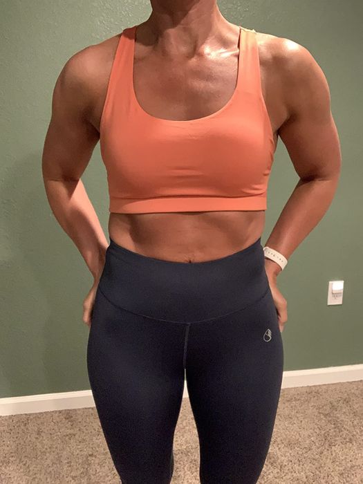 The reviewer is wearing the orange sports bra, showing the front view.