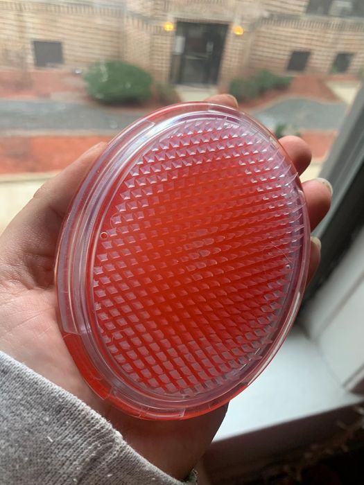 Reviewer's photo of them holding an exfoliating brush in orange color