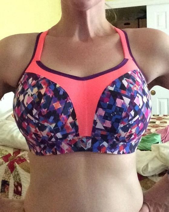The reviewer is wearing an underwire sports bra featuring a stylish pink and purple pattern on the front.