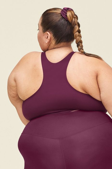 A back view of the model in a berry sports bra and matching leggings.