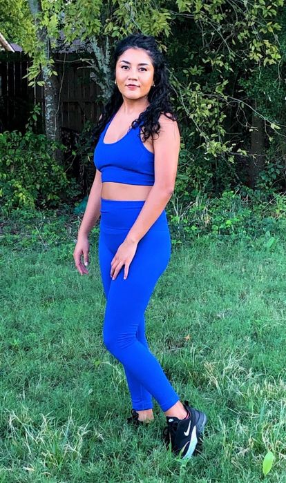 The reviewer is wearing a deep blue, matching sports bra and leggings set.