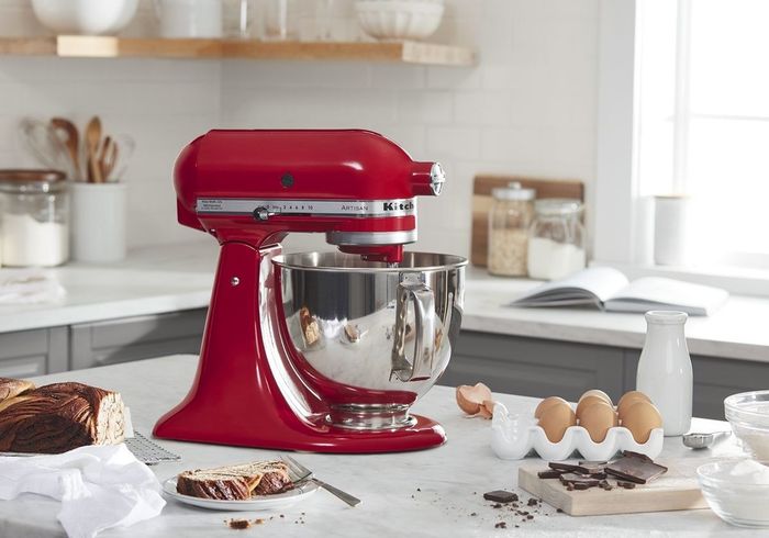 A red KitchenAid mixer placed on a white kitchen countertop.