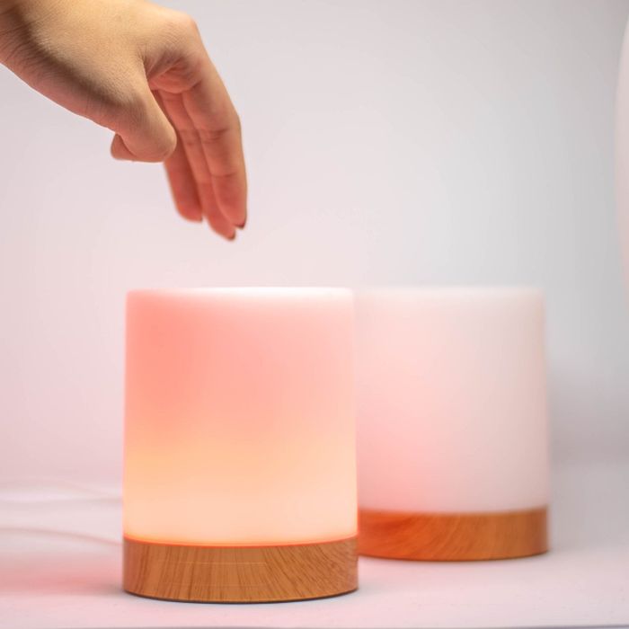 A person reaches out to touch one of the glowing friendship lamps, which is lit up in a warm red hue.