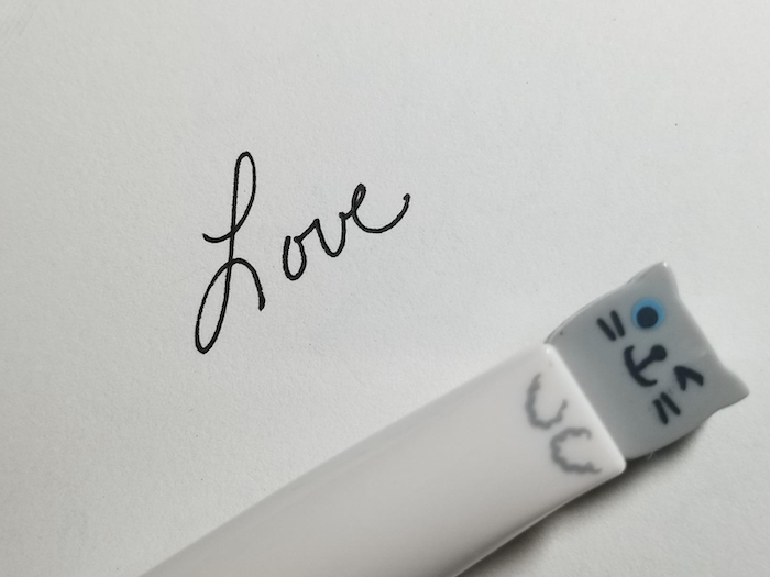 A reviewer’s close-up photo of the word 'Love' written in cursive by one of the cat pens. The ink flows smoothly, with the word 'Love' appearing solid and clear, with no ink bleeding.