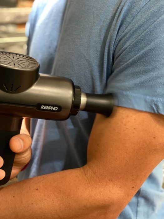 A reviewer using the massage gun on their bicep