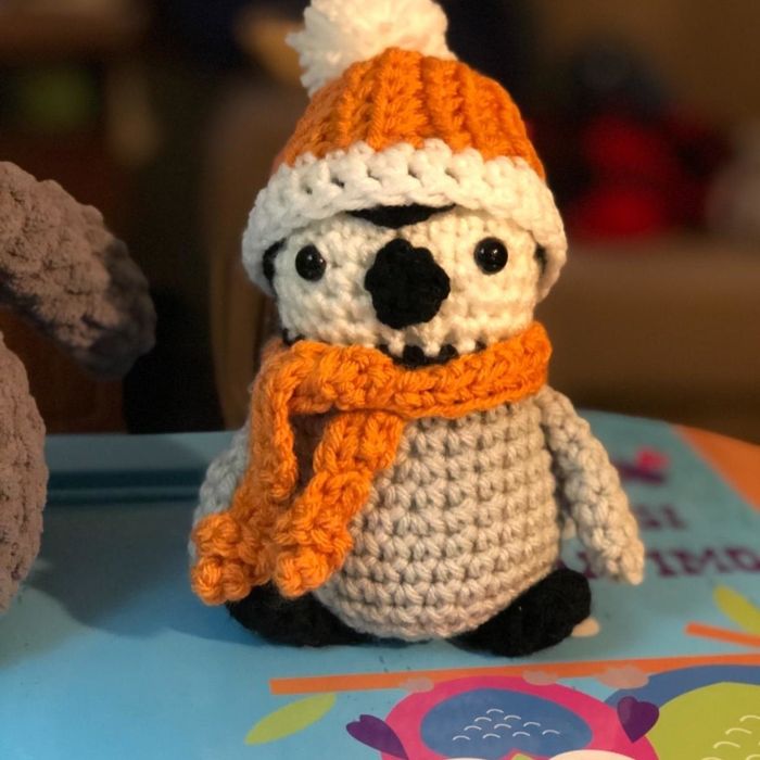Reviewer’s photo of a crochet penguin wearing a cozy beanie and an orange scarf.