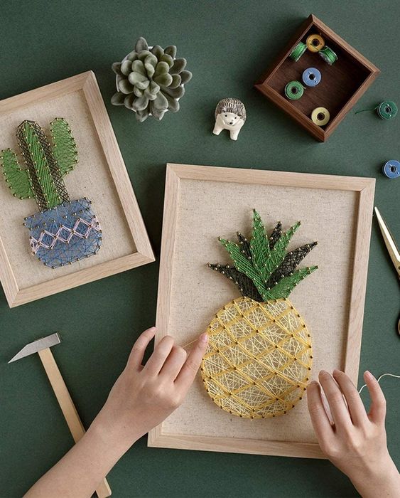 A model working on creating a pineapple design with string art.