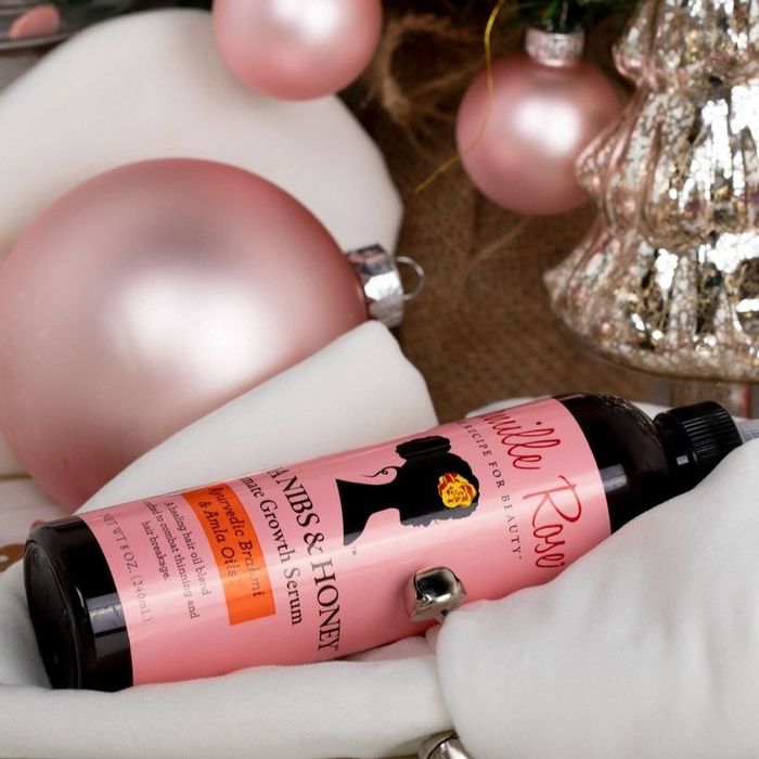A bottle of luxurious hair growth serum adorned with pink and gold accents.