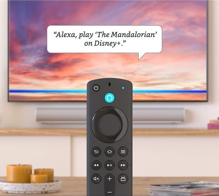 The Fire Stick displayed in front of a TV screen with a dialogue that reads, 'Alexa, play The Mandalorian on Disney+'.