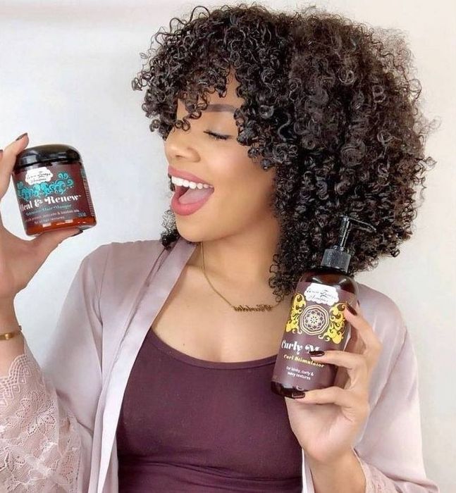 A person holding a jar and a bottle of hair products.
