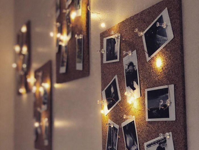 A photo showing twinkle lights adorning cork boards, framed with Polaroid pictures.