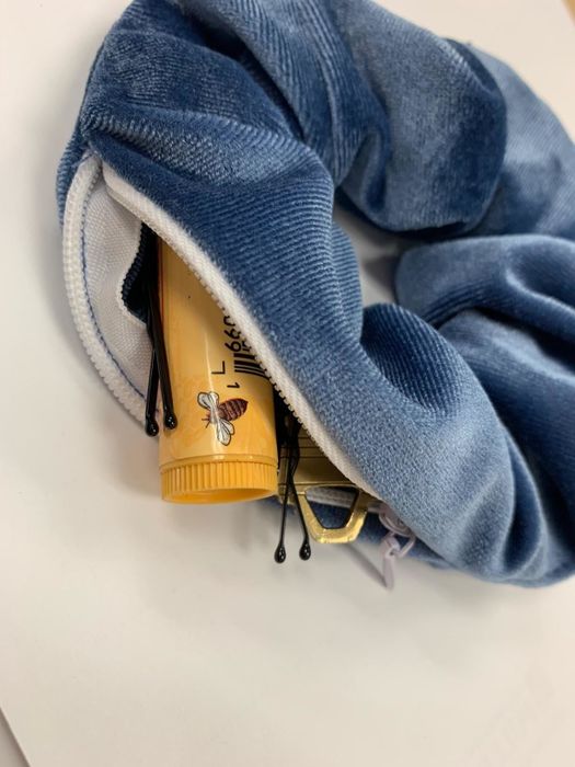 A reviewer’s photo of the scrunchie with the zipper open, revealing hidden treasures like bobby pins and chapstick inside.