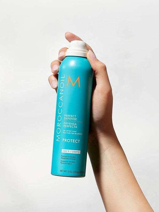 A hand holding a bottle of the heat protectant.