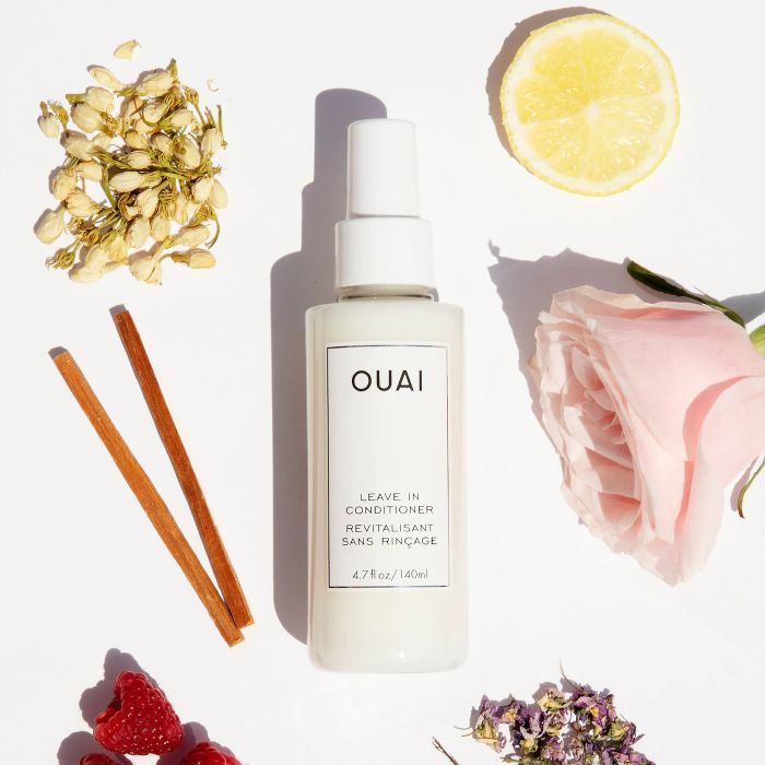 A bottle of leave-in conditioner surrounded by ingredients.
