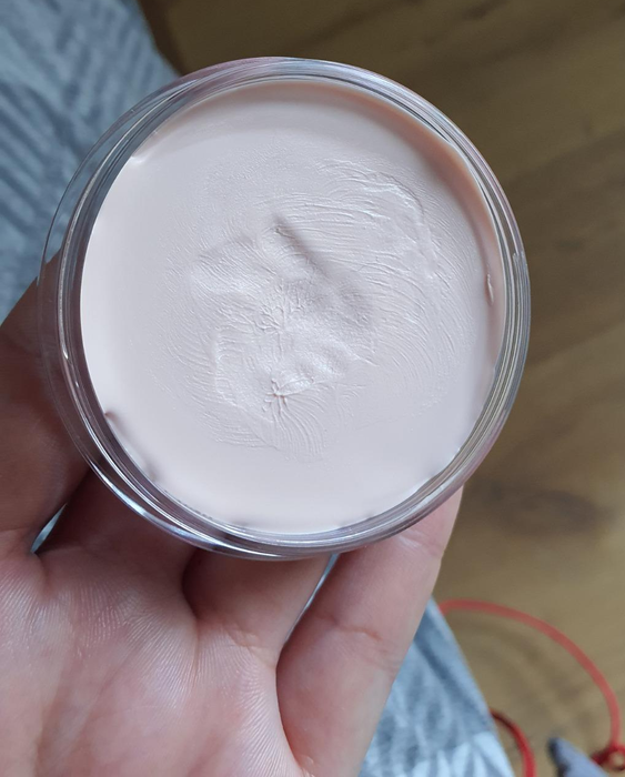 A reviewer holding a small container of the primer.