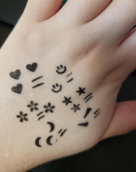 A reviewer displaying the stamps and eyeliner applied on the back of their hand.