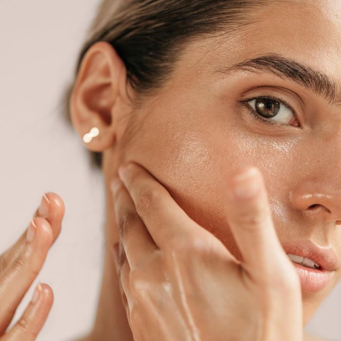 Close-up of a model applying skincare product to their cheek