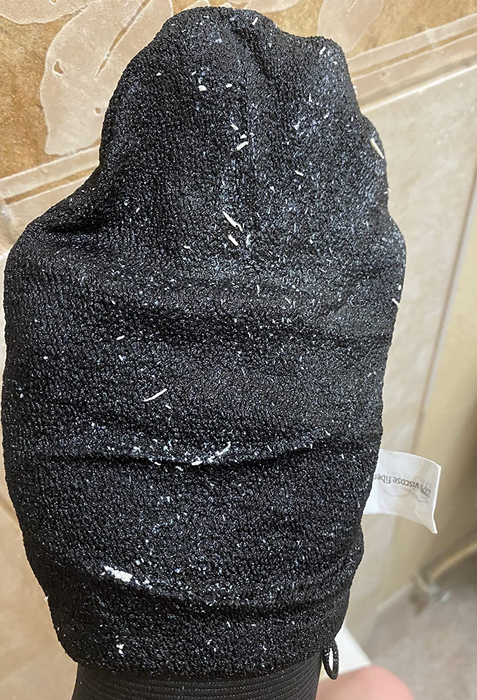 A reviewer's hand inside a black mitt, which is covered in dead skin