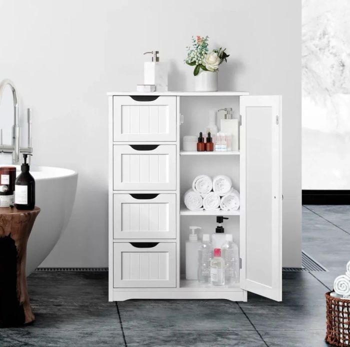 a white wooden bathroom storage cabinet stocked with towels and toiletries