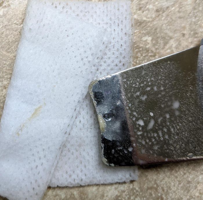 Reviewer's scraper after use, showing the dirt and oil removed from the skin.