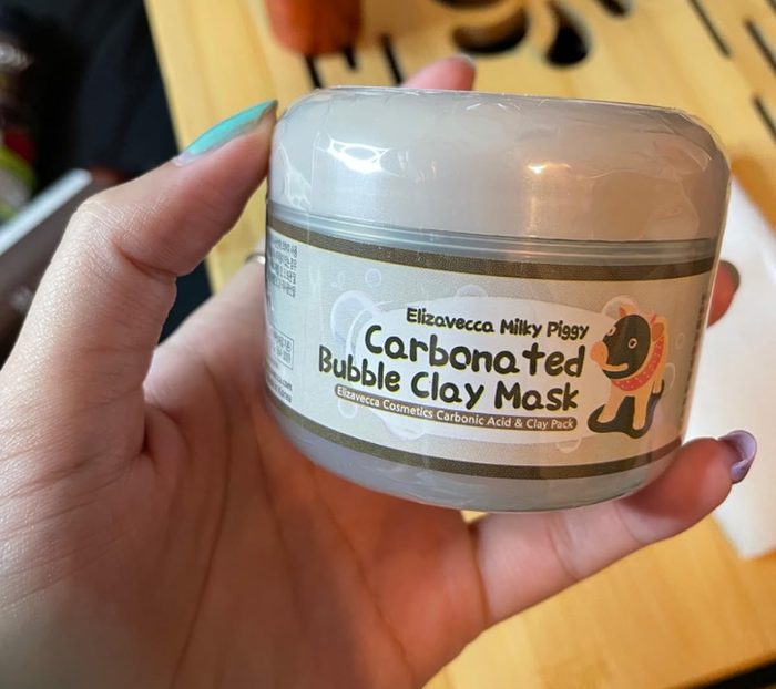 reviewer holding a container of the clay mask
