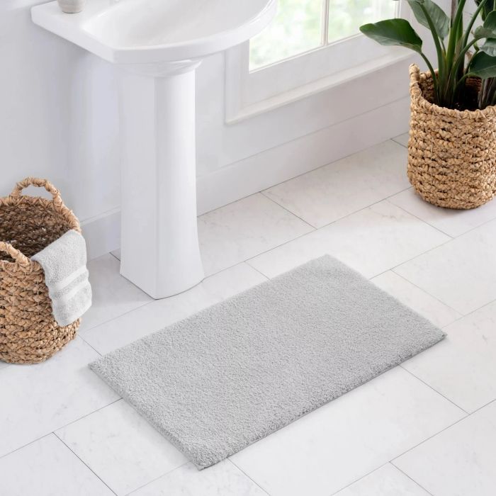 A gray bath mat placed neatly in front of the sink.