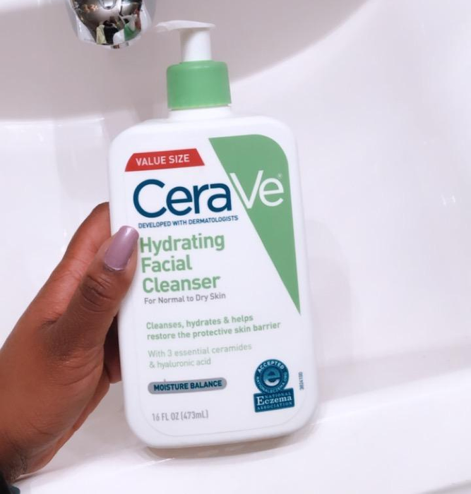 A reviewer holding the white and green cleanser bottle