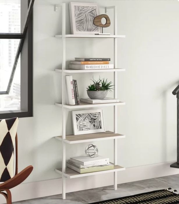 A white, five-tier bookcase with books, frames, and decorative accents