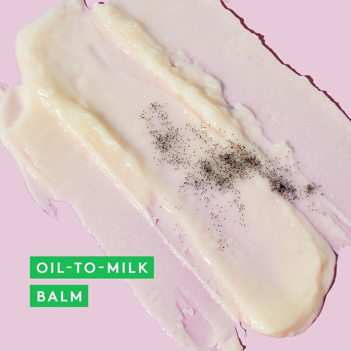 Smear of oil-to-milk balm with specks on a pink background and a green text box overlay reading
