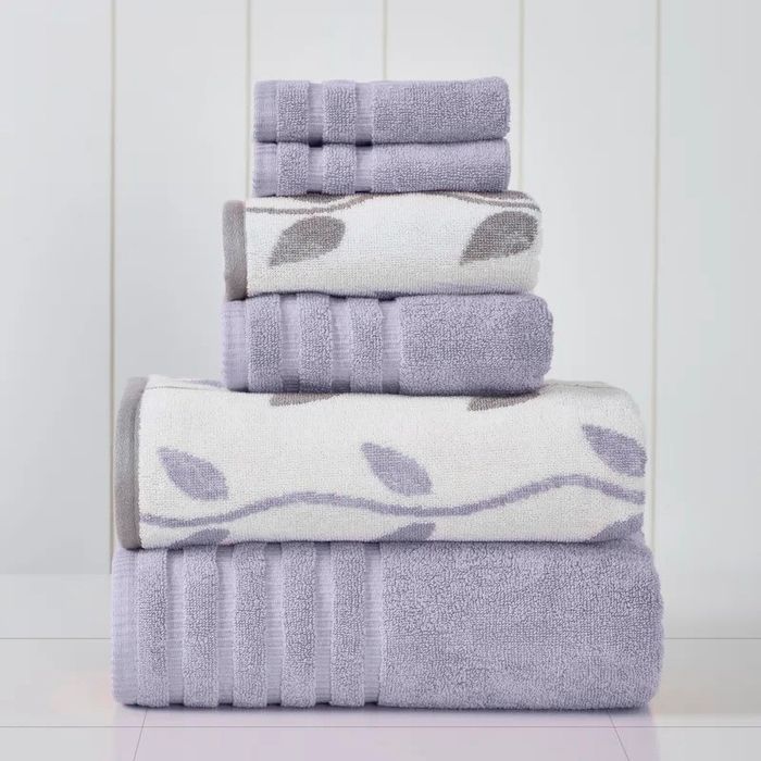 A neat arrangement of towels of varying sizes and patterns. The topmost towels feature leaf patterns, while the others remain solid-colored.