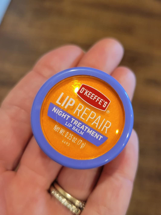 Reviewer holding the tin of O'Keeffe's Lip Repair balm, ready to nourish their lips