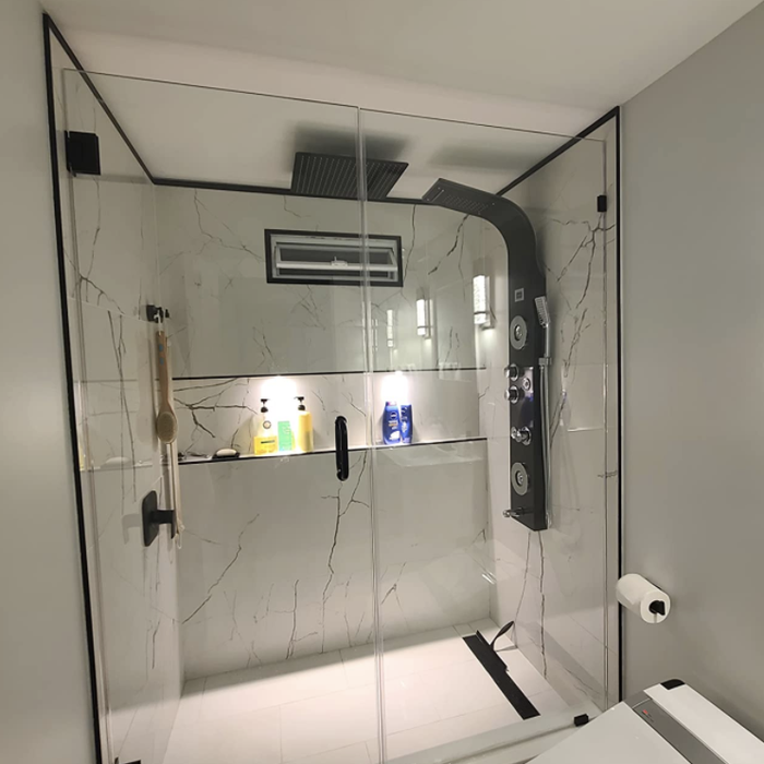 A marble shower featuring a sleek panel on one of the walls