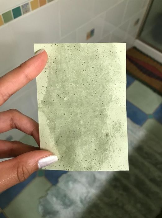 the same customer displays a green oil-blotting sheet soaked with oil extracted from their forehead