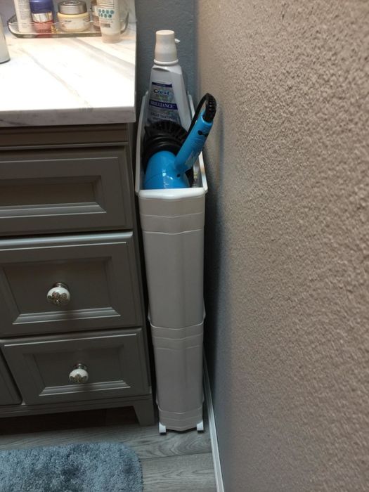 reviewer's white storage tower with bathroom necessities tucked into the space between the vanity and the wall