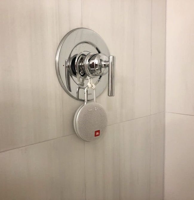 A user's Bluetooth speaker attached to their shower's faucet, creating a tranquil sound experience during their shower routine.