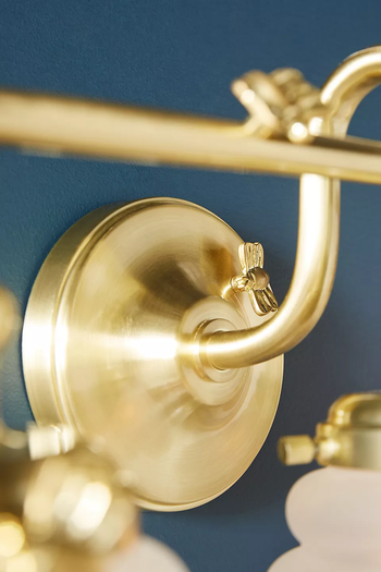 A close-up of a small gold bee attached to a sconce