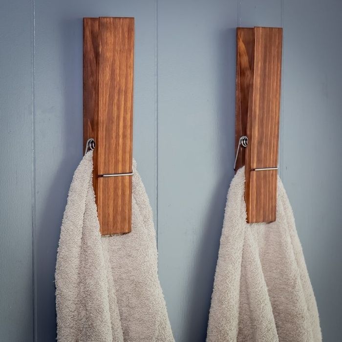 Two oversized clothespin towel holders placed on a bathroom wall