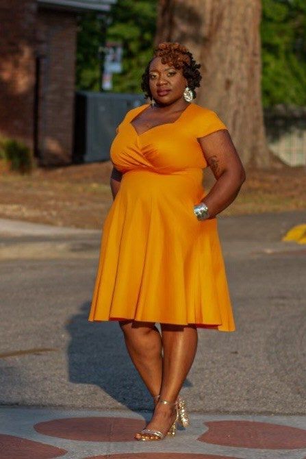 A reviewer showcases the dress in a bold orange shade.