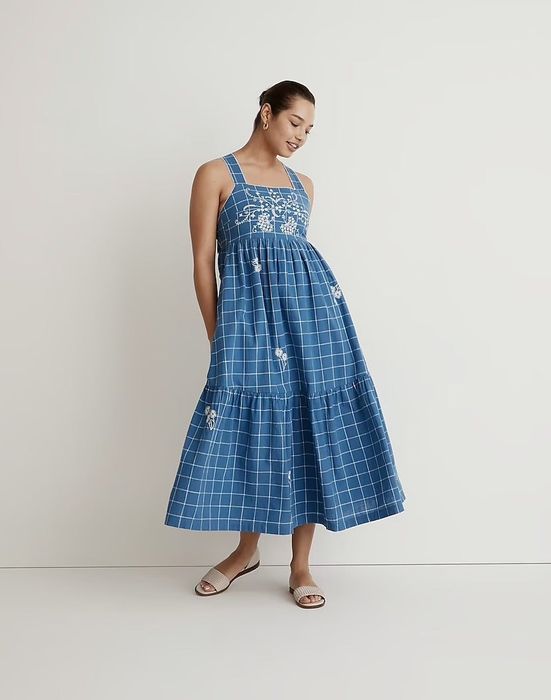 A model wears the blue dress decorated with detailed embroidery.