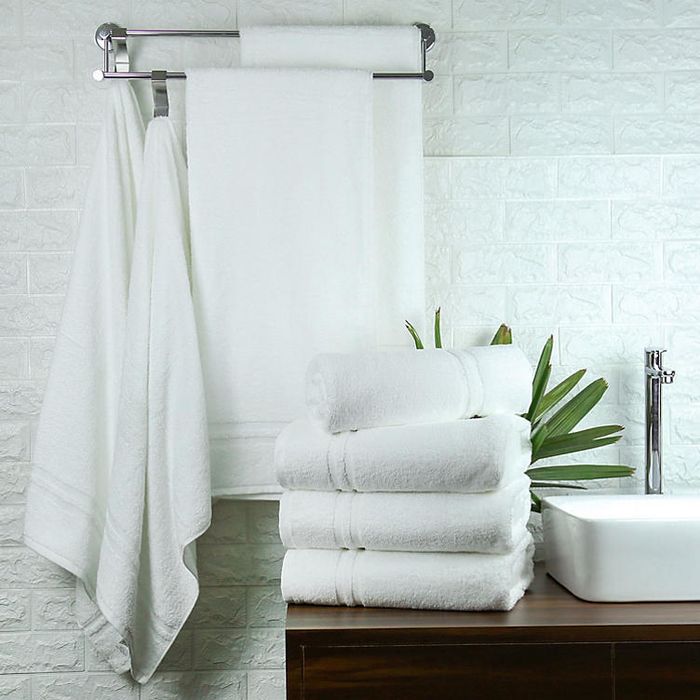 Four white bathroom towels arranged on a bathroom counter.