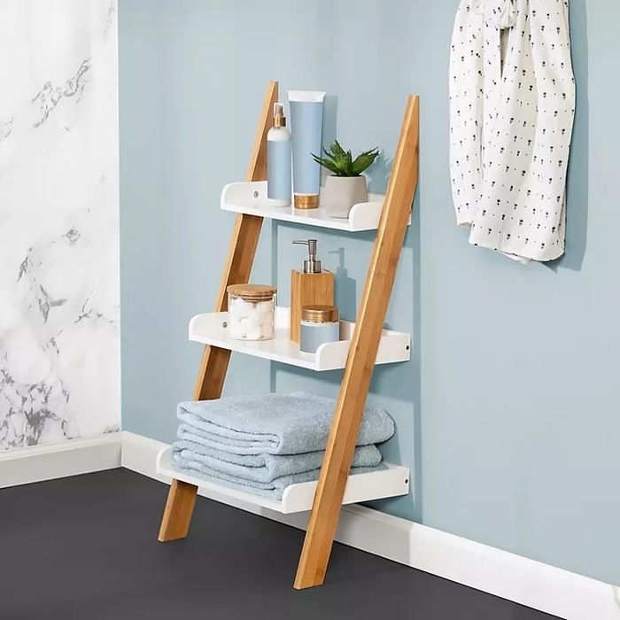 A ladder shelf in a bathroom, holding towels, soap, and various other bathroom essentials.