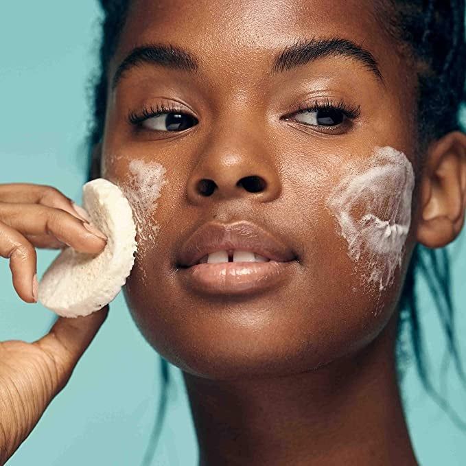 a model gently massaging a cleansing bar over their cheeks