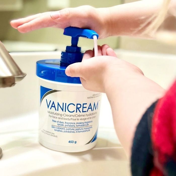 A hand dispensing the skin cream using its pump nozzle.